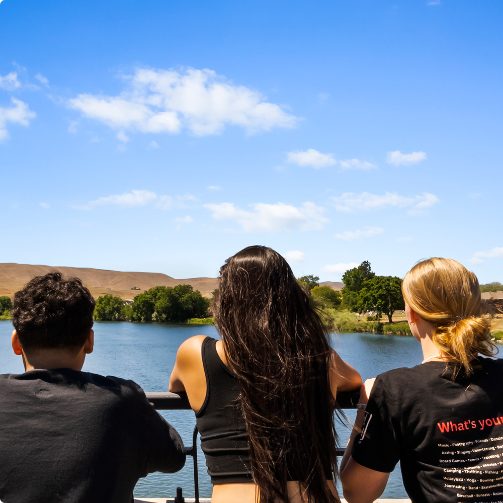 Three people enjoying a scenic lake view.