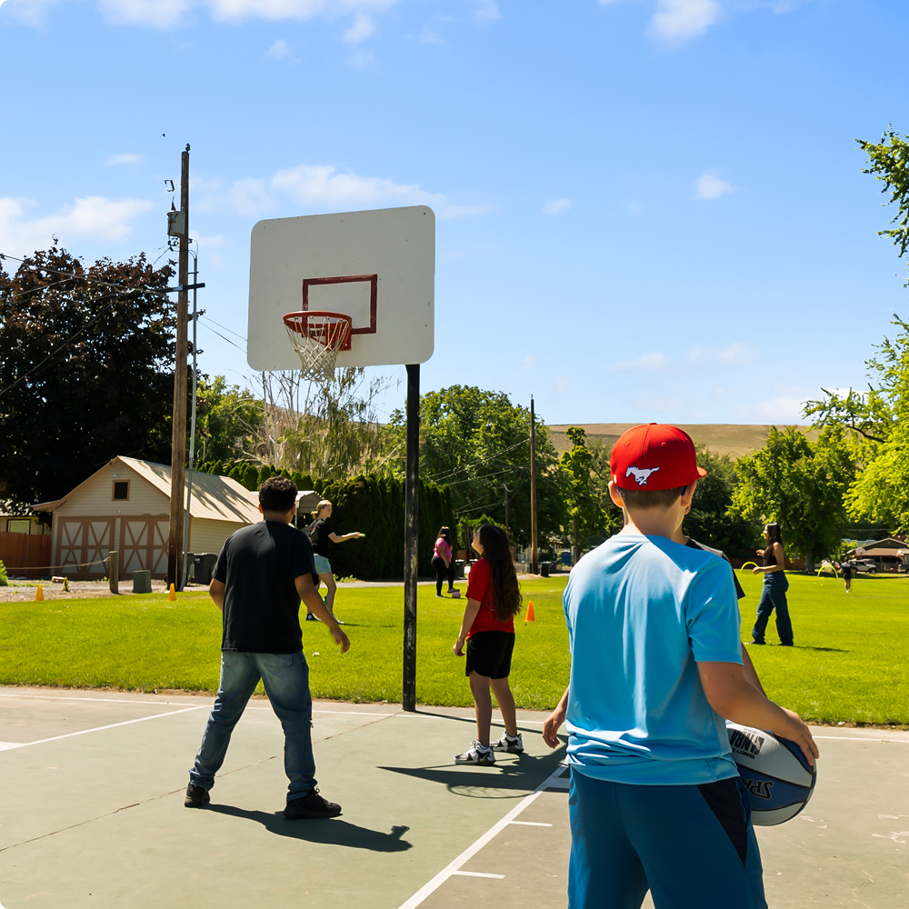 Kids playing basketball outdoors on sunny day