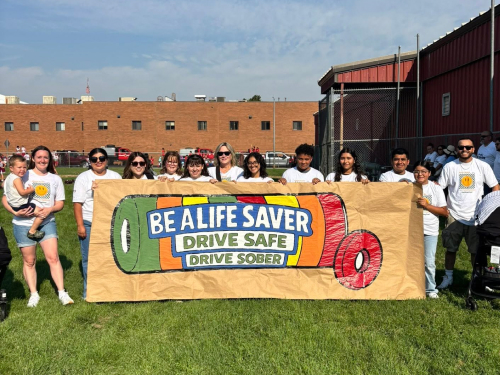 Group with safe driving banner at outdoor event.