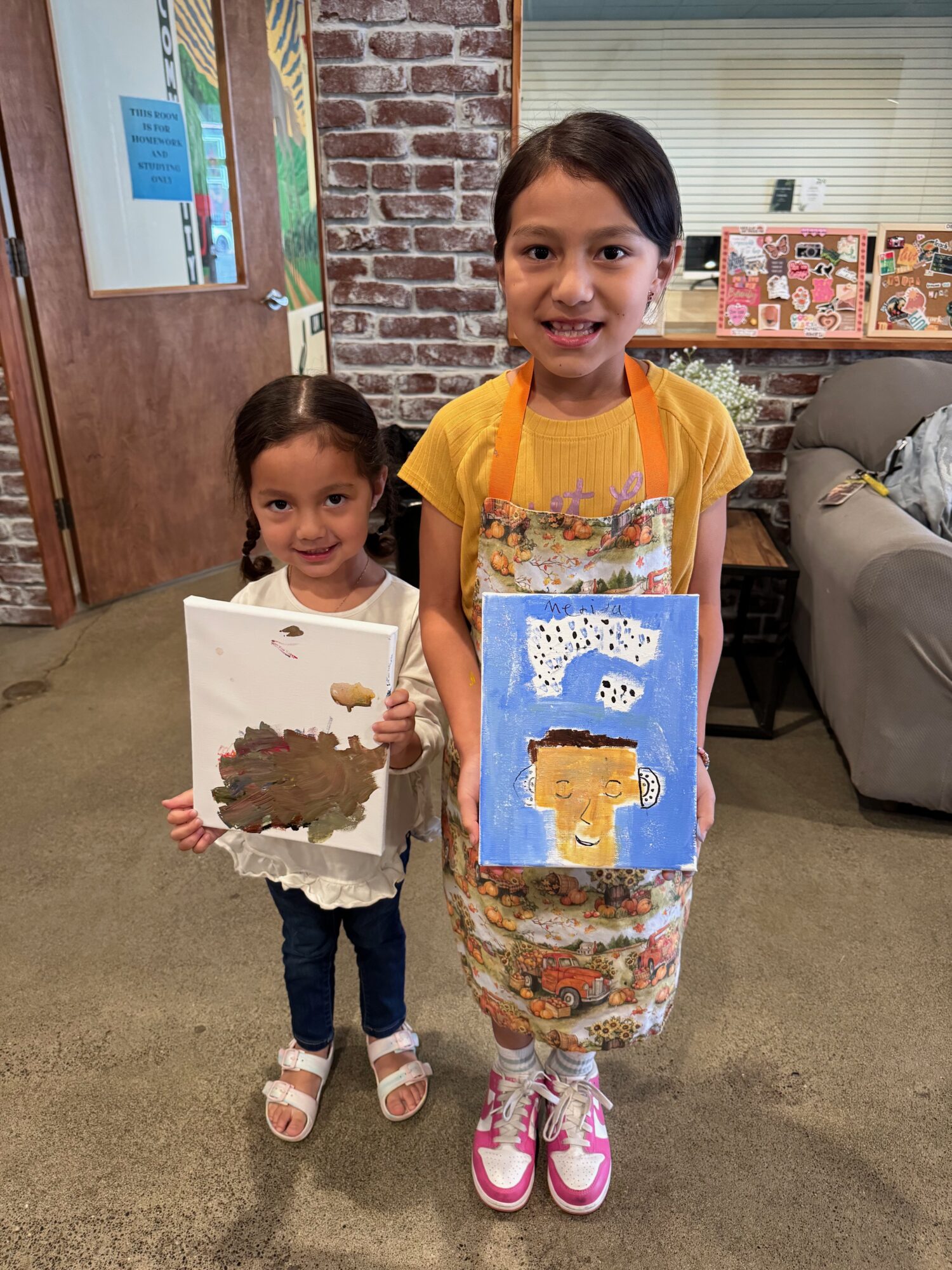 Two kids proudly display their painted artworks.