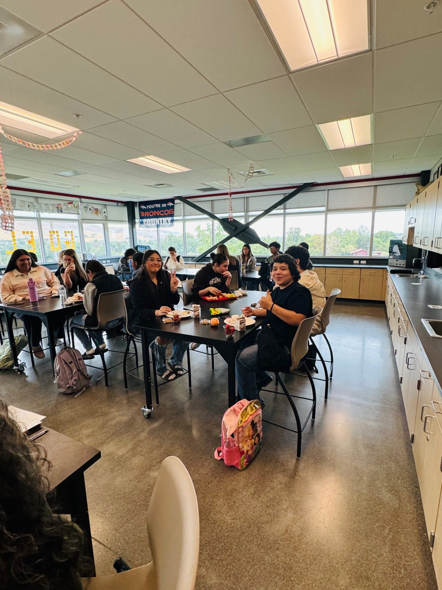 Students studying in a classroom with a Broncos poster.