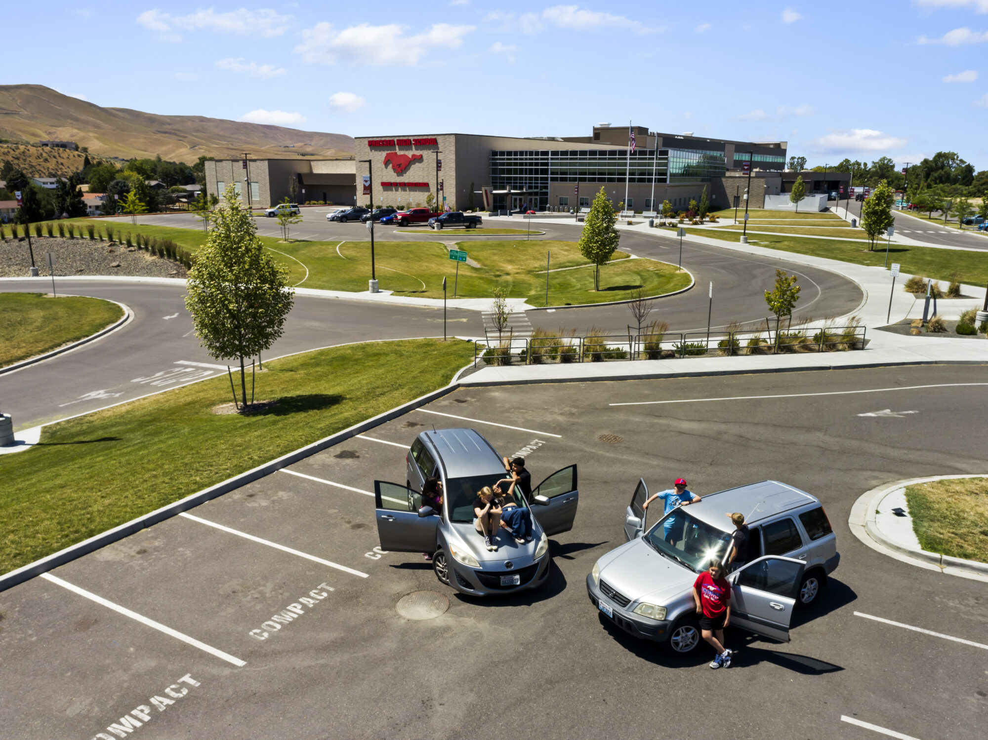 High school parking lot with cars and students.