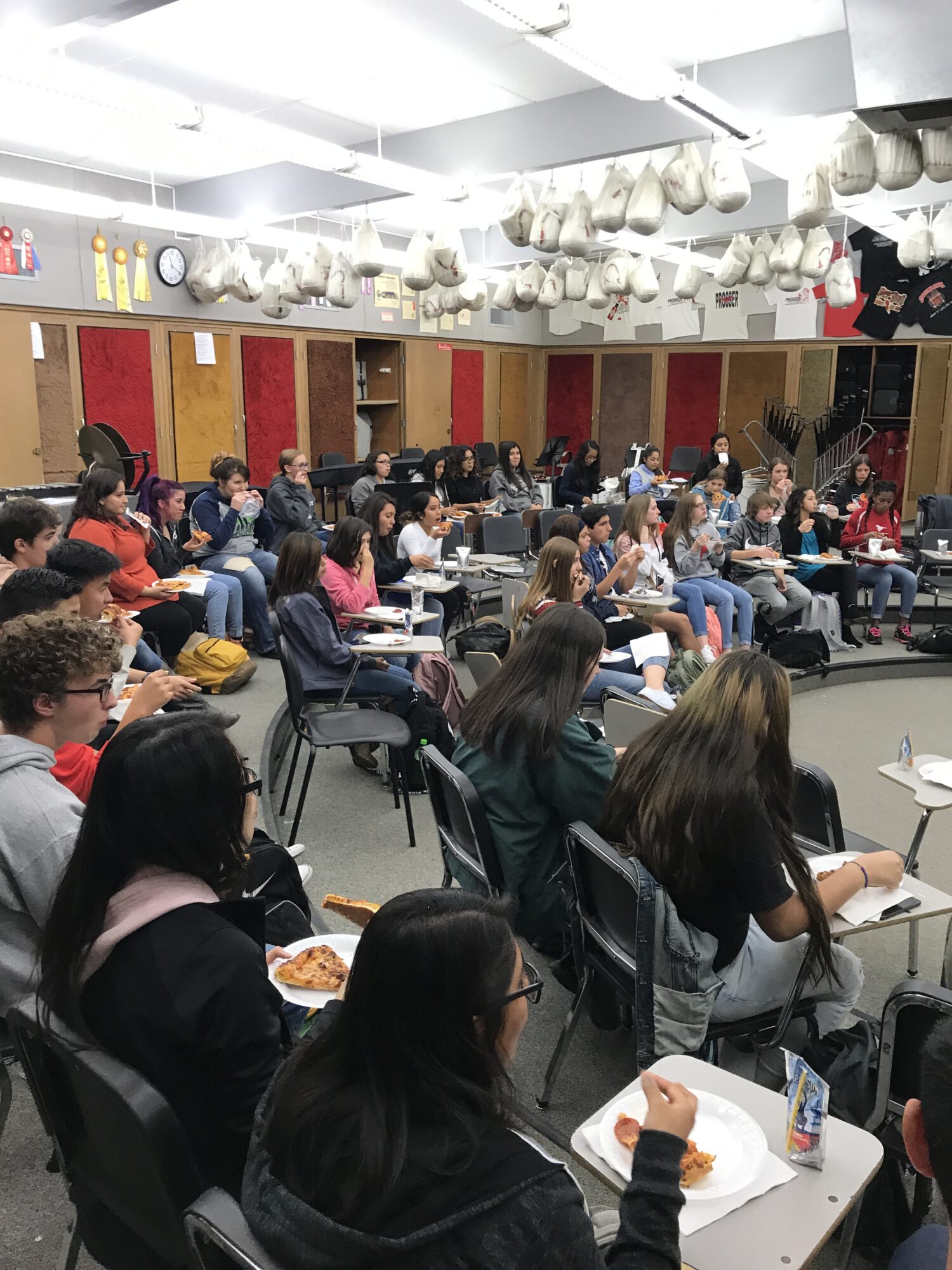 Students eating pizza in a classroom setting.
