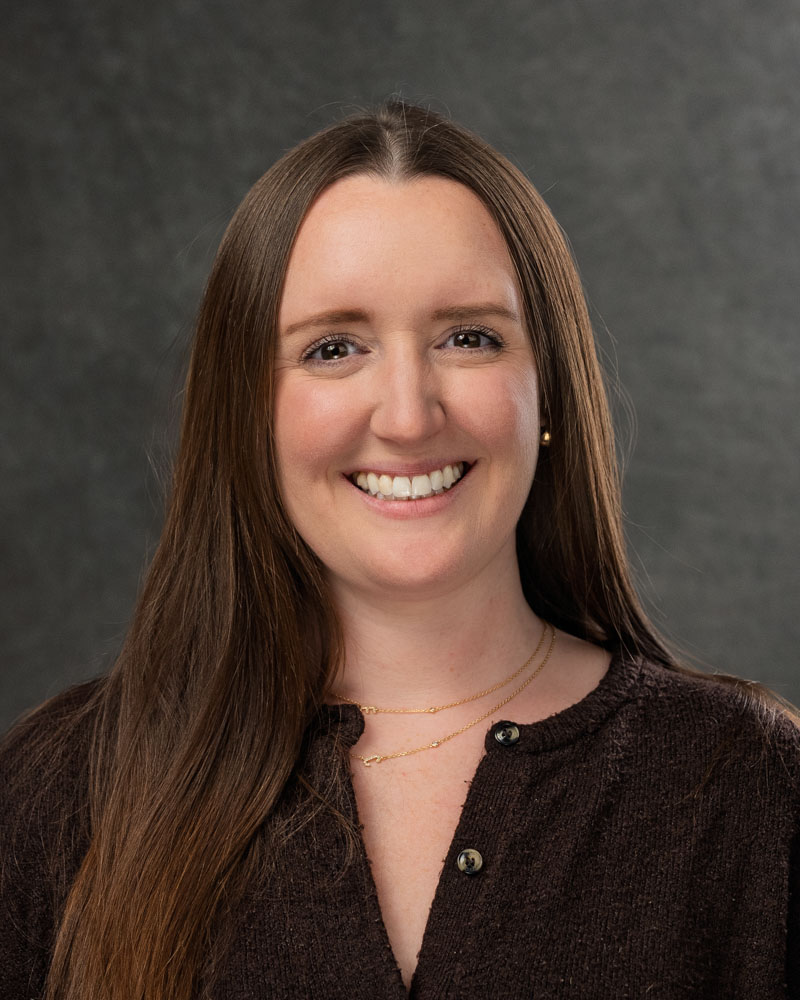 Smiling woman with brown hair and sweater.