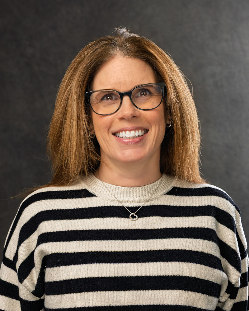 Smiling woman in striped sweater and glasses.