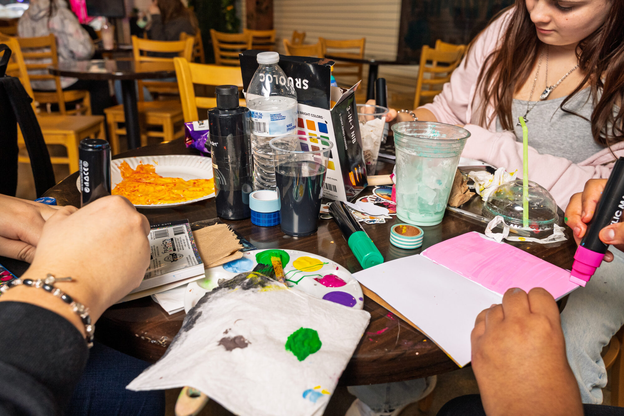People painting and crafting at a wooden table.
