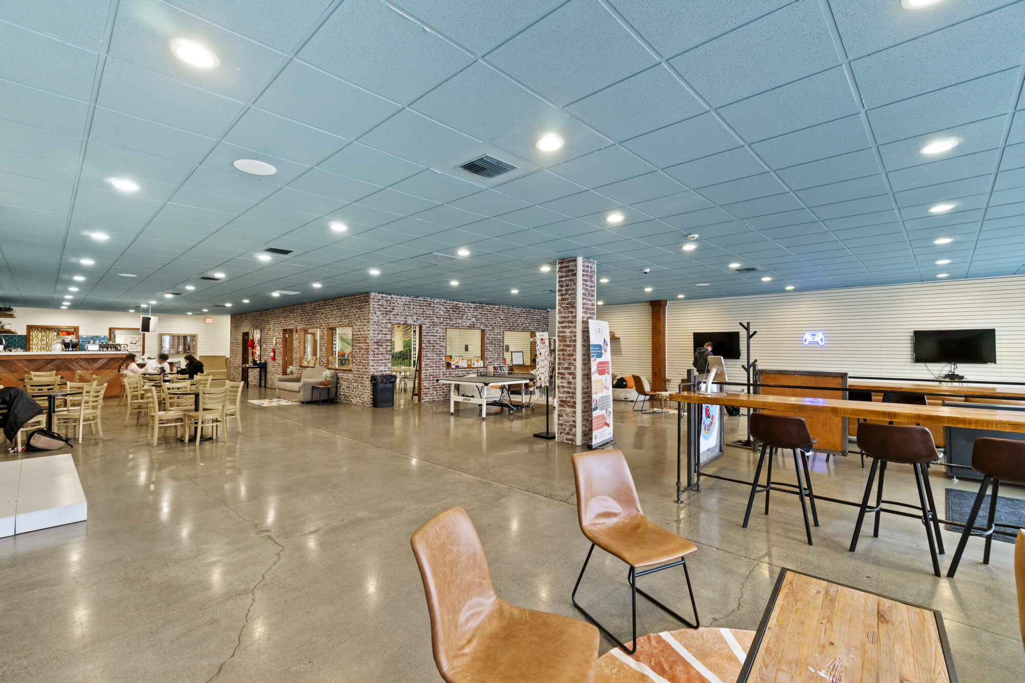 Spacious cafe interior with seating and brick accents.