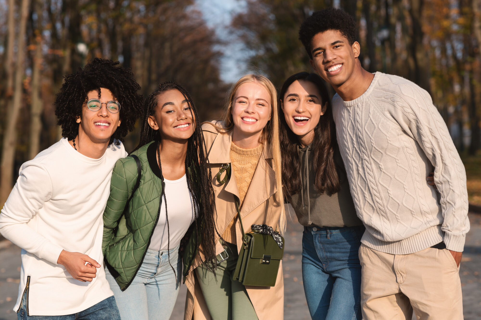 Diverse friends smiling outdoors in autumn park
