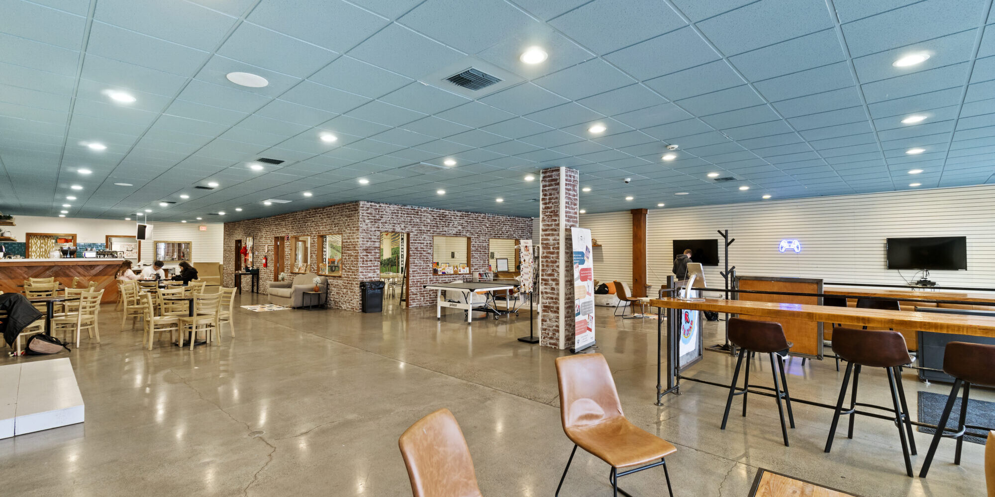 Spacious cafe interior with seating and brick accents.